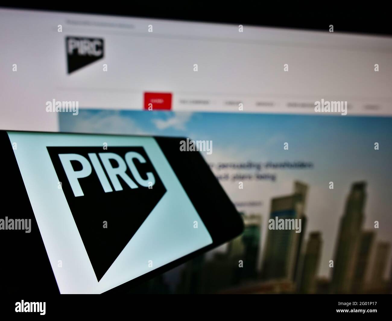 Smartphone with logo of Pensions and Investment Research Consultants Ltd (PIRC) on screen in front of website. Focus on center-left of phone display. Stock Photo