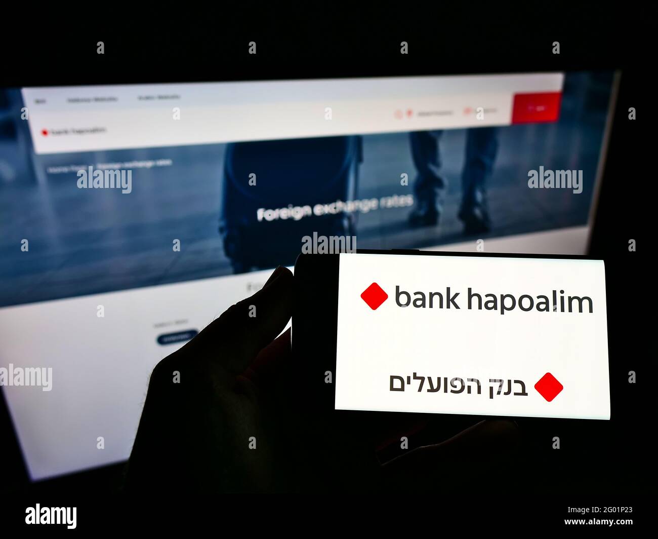 Person holding smartphone with logo of Israeli financial company Bank Hapoalim BM on screen in front of business webpage. Focus on phone display. Stock Photo