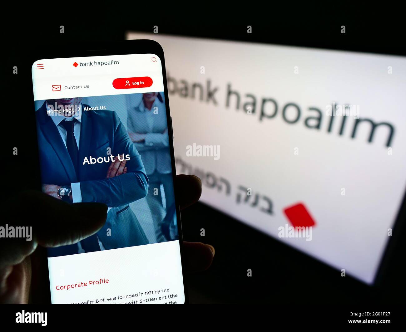 Person holding mobile phone with website of Israeli financial company Bank Hapoalim BM on screen in front of logo. Focus on center of phone display. Stock Photo