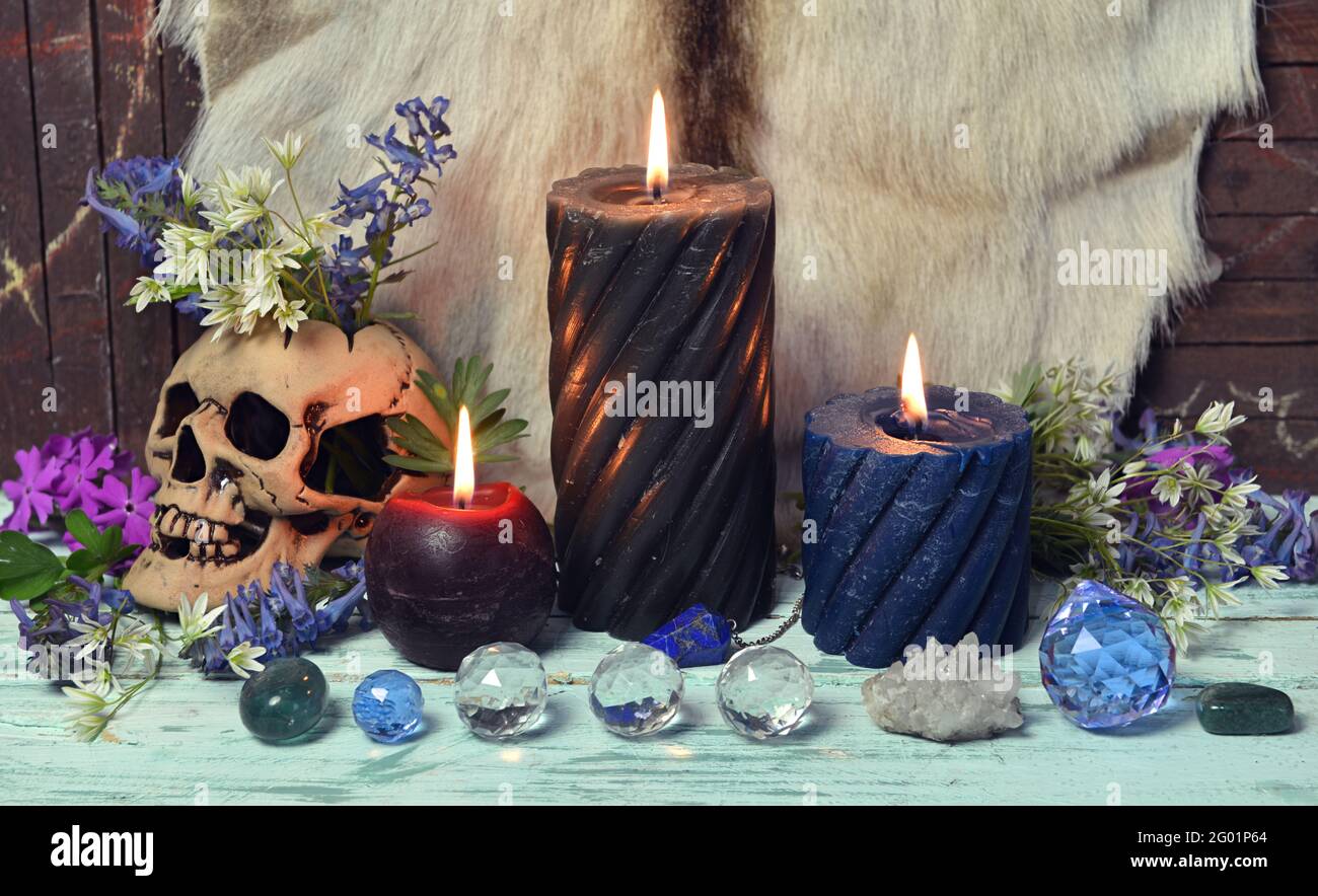 Still life with crystal stones, burning candles and skull with flowers ...