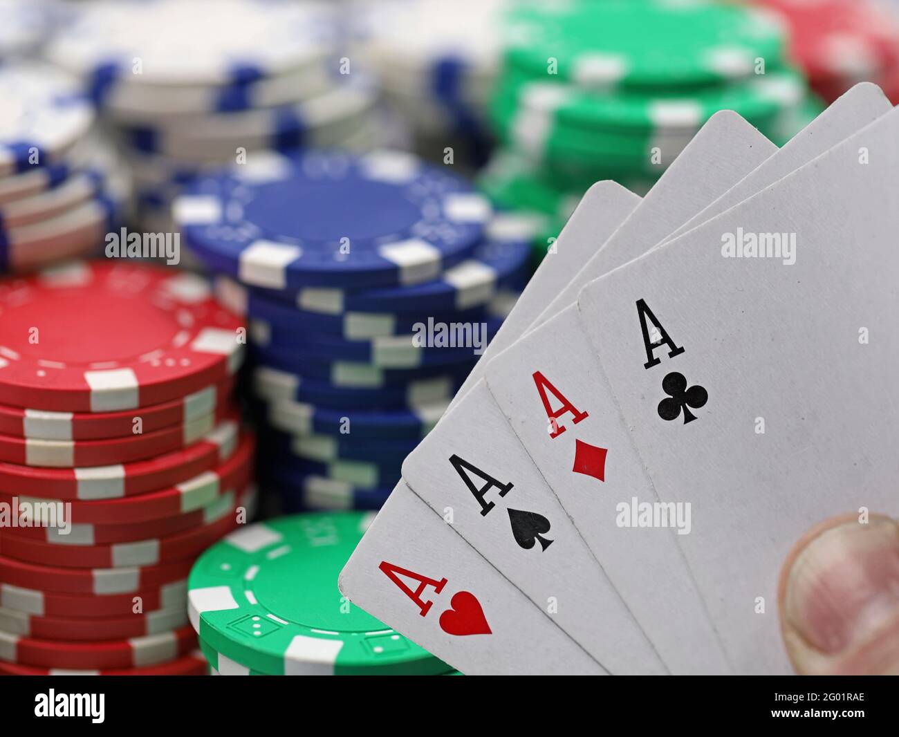 four aces card combination holden in front of stacked casino chips Stock Photo