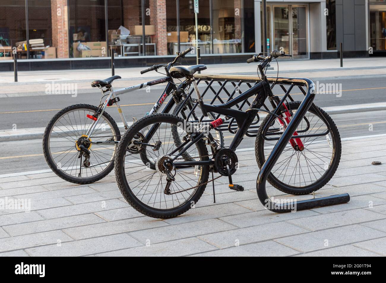 Ottawa, Canada May 23, 2021: Bike rack for parking bicycles in the street of downtown. Bycycle stand with locked vehicles on pavement near road in the Stock Photo