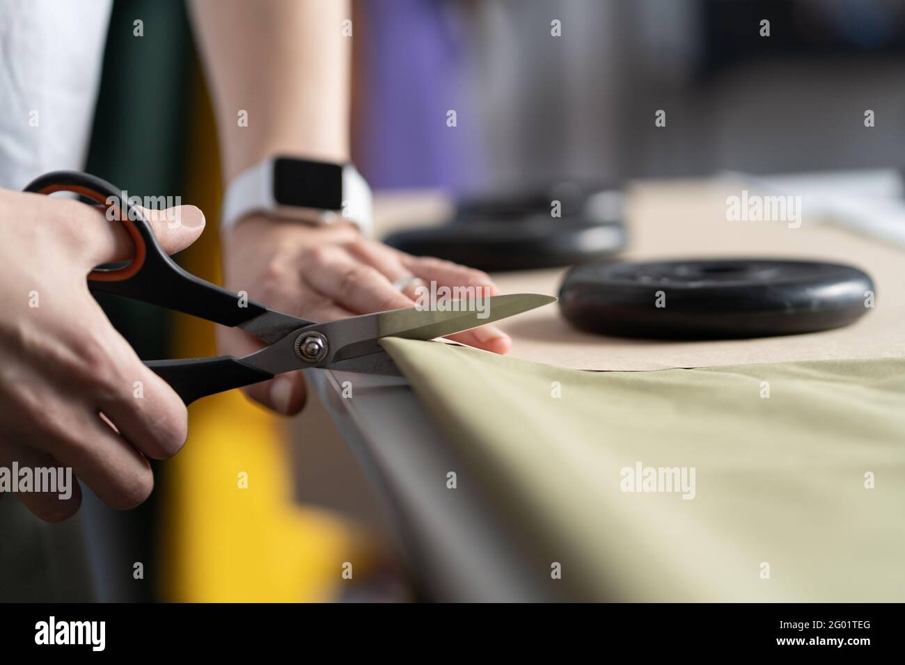 Female dressmaker cut fabric for clothes in tailor studio. Freelance