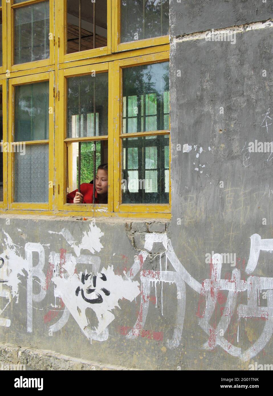 Chinese school girl looking outside the window of the classroom Stock Photo