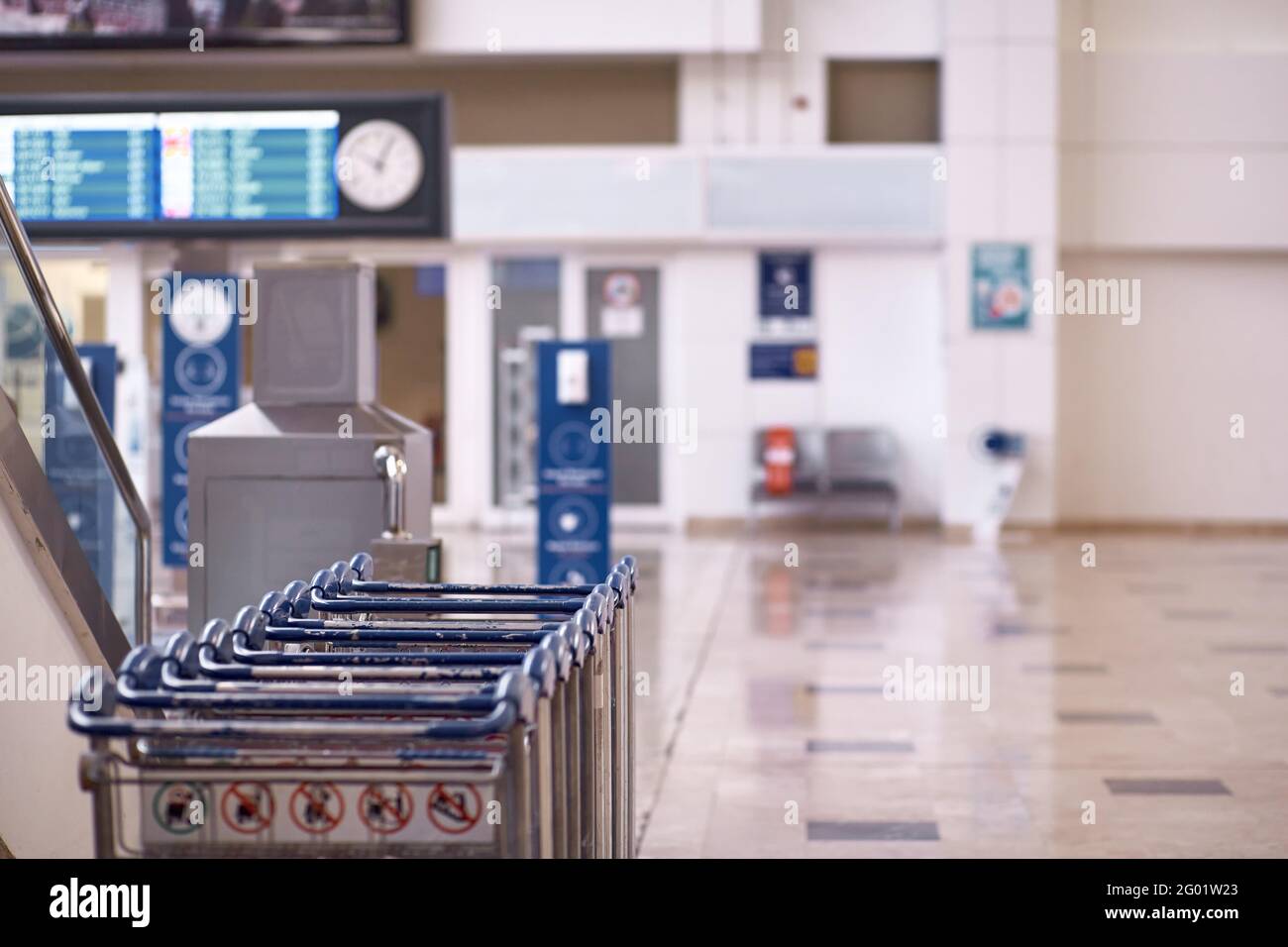 Airport luggage trolleys, flight schedules and wall clocks with copy space. Selective focus. High quality photo Stock Photo