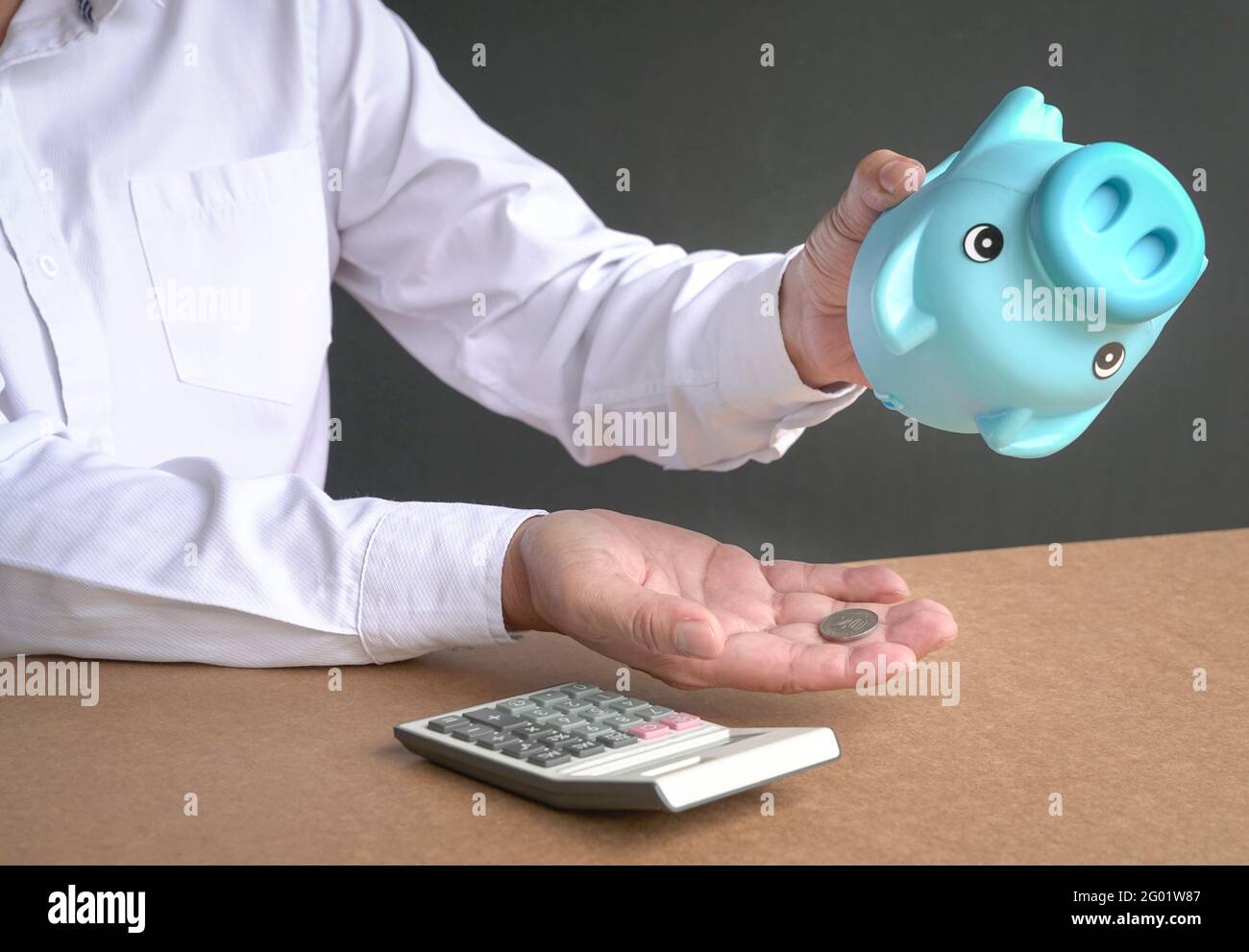 Businessman emptying piggybank savings. Only one coin left. Broke or financial crisis concept. Stock Photo
