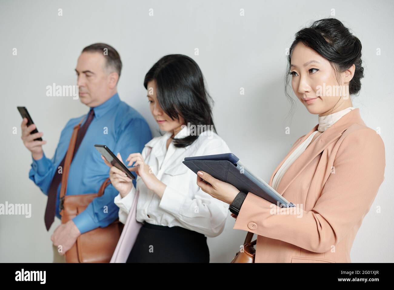 Skeptical discontented young businesswoman standing in queue with tablet computer in hands Stock Photo