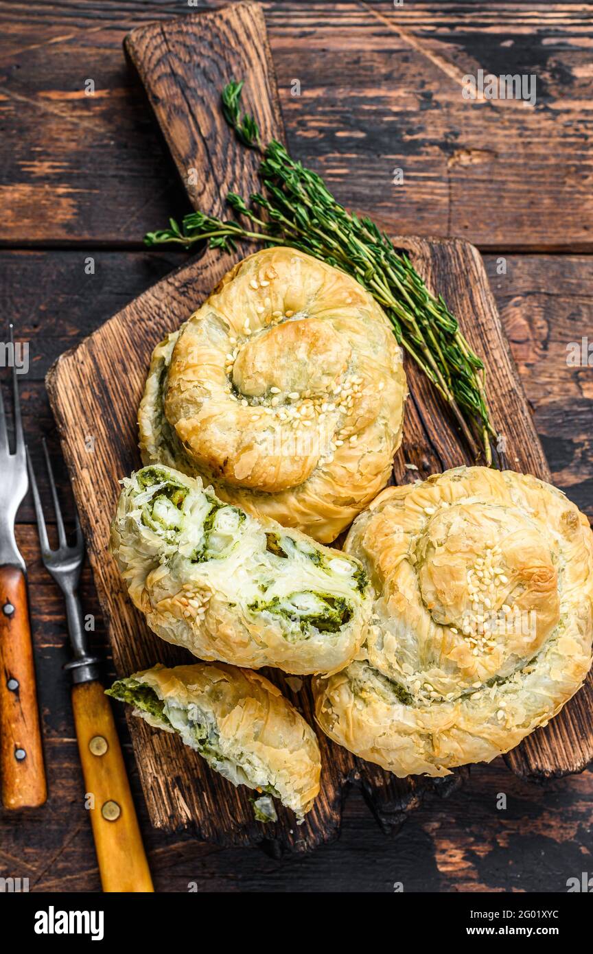 Baked spiral filo pastry puff with feta cheese and spinach. Dark wooden