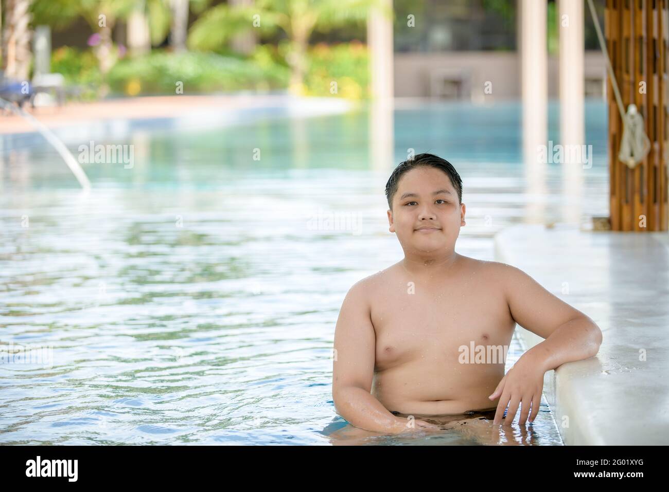 Happy obese boy sit on chair at pool bar in swimming pool, relax and rest  on summer concept Stock Photo - Alamy