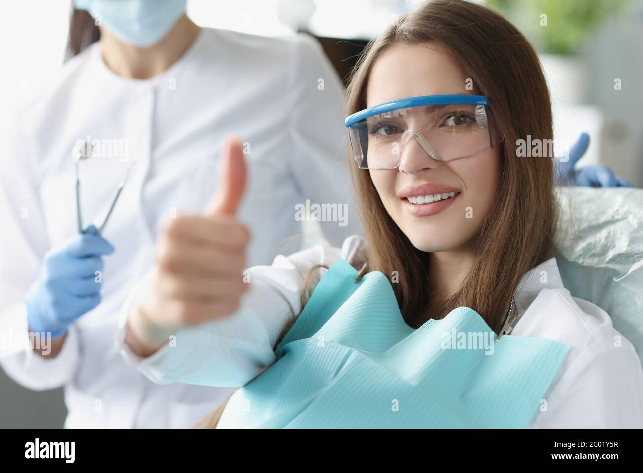 Portrait of smiling woman holding her thumbs up at dentist appointment Stock Photo