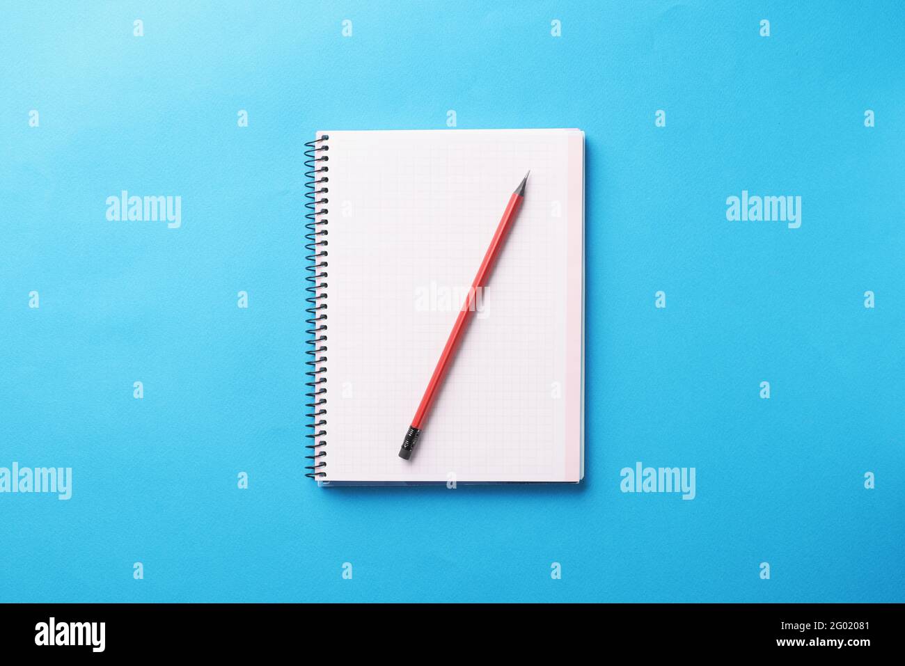 White notebook with wooden pencil lies on blue background Stock Photo