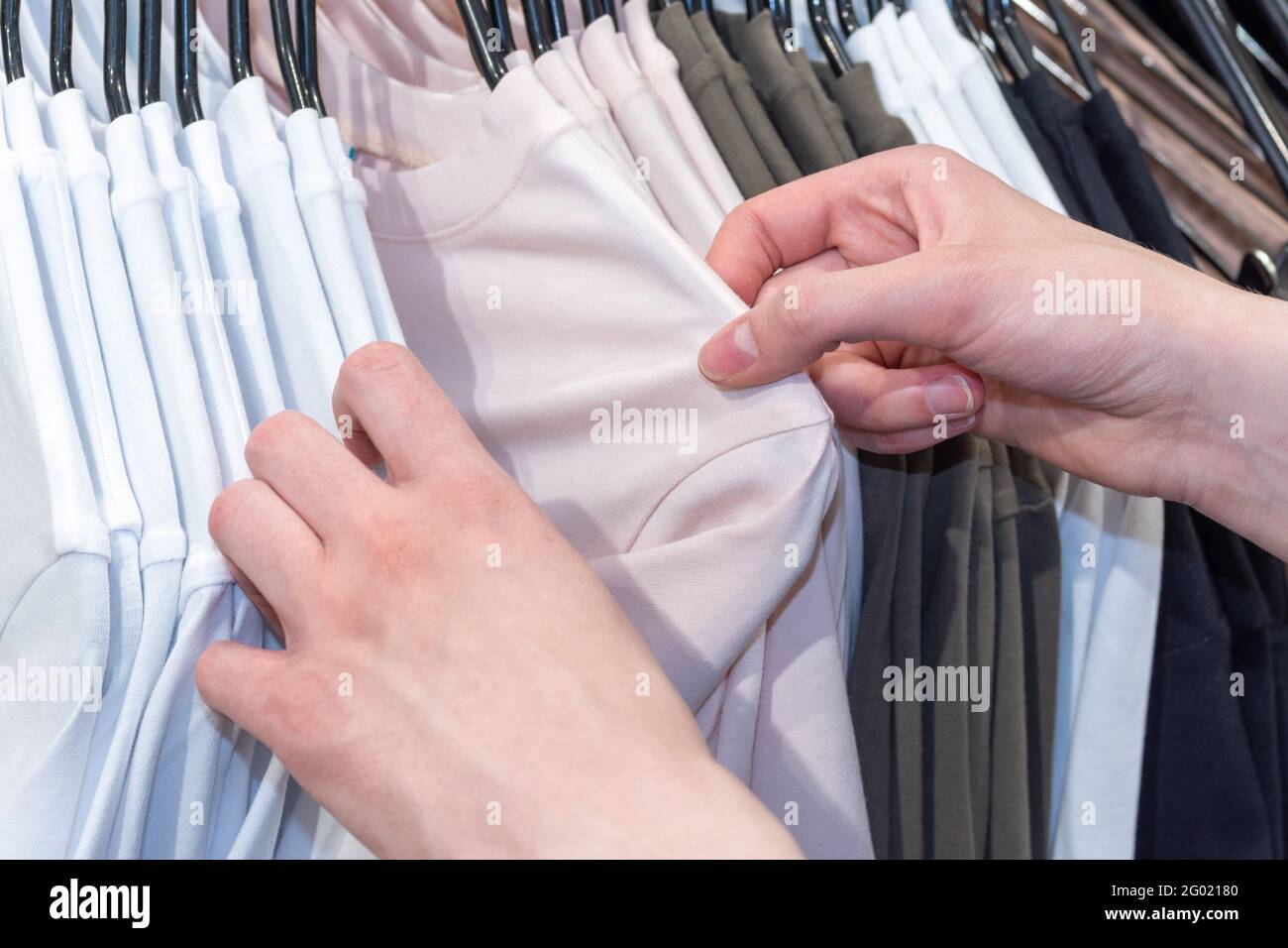 Shopping, fashion, style - Women's hands are choosing clothes hanging on a hanger in the store. Business concept. Stock Photo