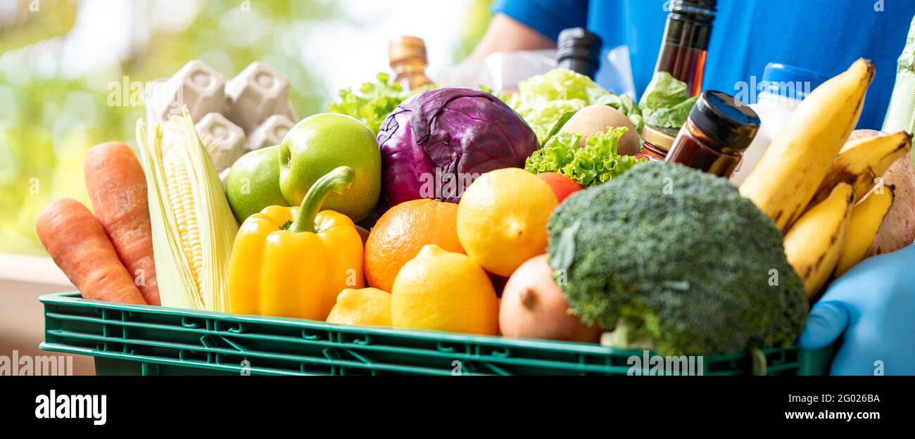 Banner image of deliveryman holding grocery basket ready to deliver to customer, food delivery service concept Stock Photo