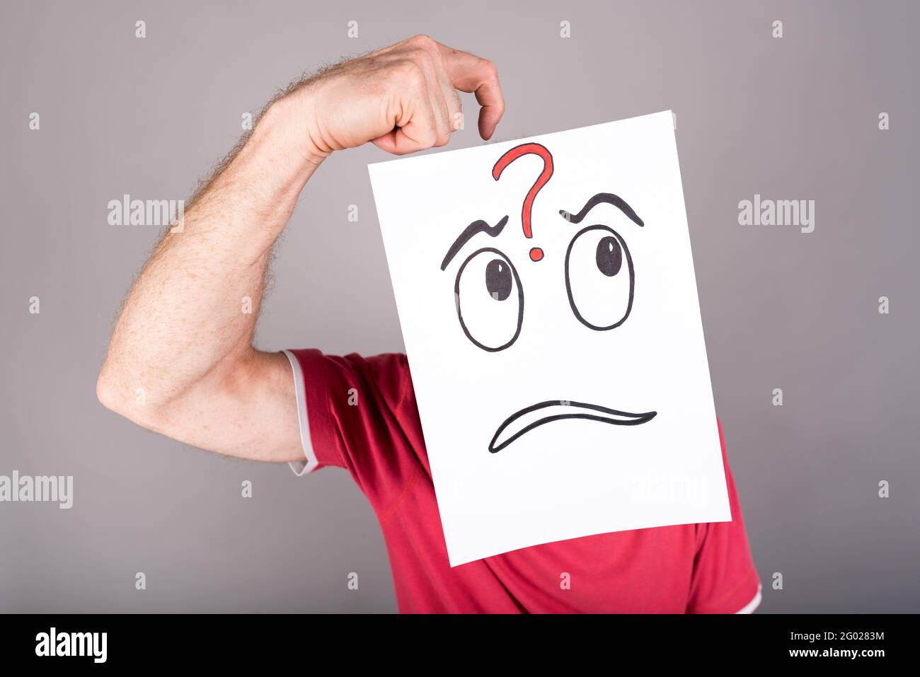 Man behind a paper with a questioning expression Stock Photo - Alamy