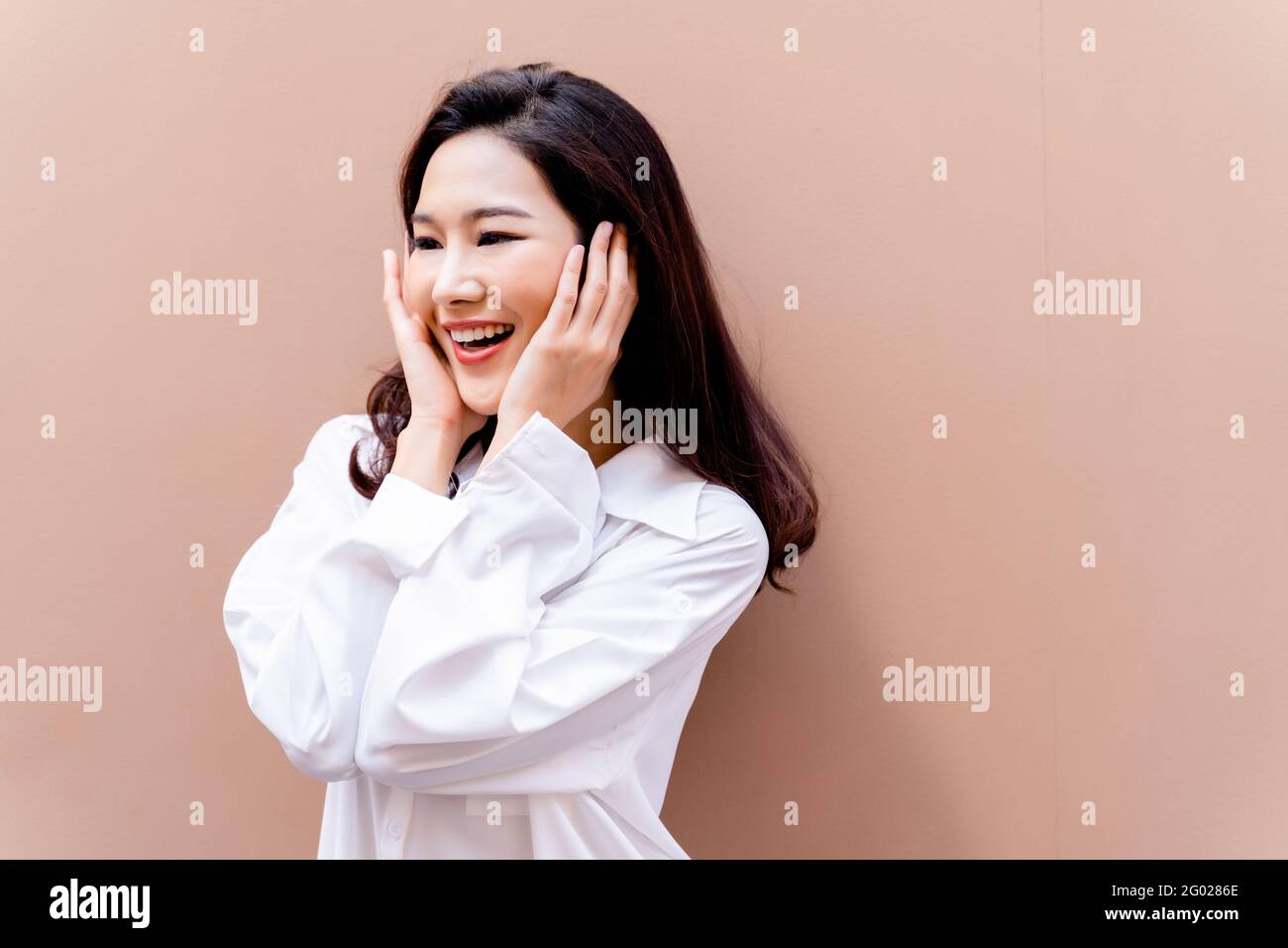20s young Asian happy millenial woman in white shirt in clean background smiling and laughing confidently with beautiful teeth. Portrait of beauty skin care and oral care concept Stock Photo