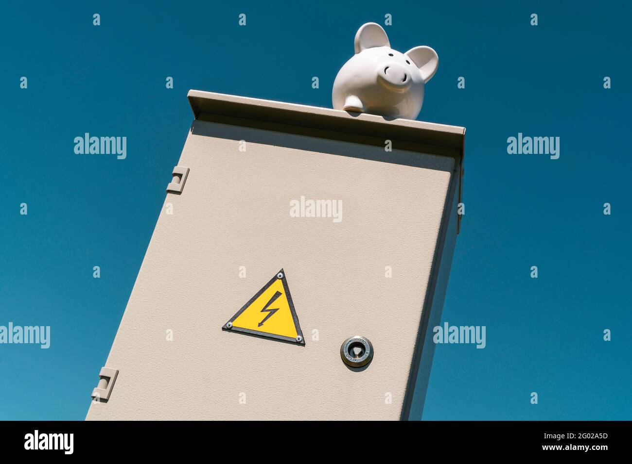 Piggy bank on the top of outdoor electric cabinet.Symbolic depiction of energy savings at home, utility bills, smart energy consumption. Stock Photo
