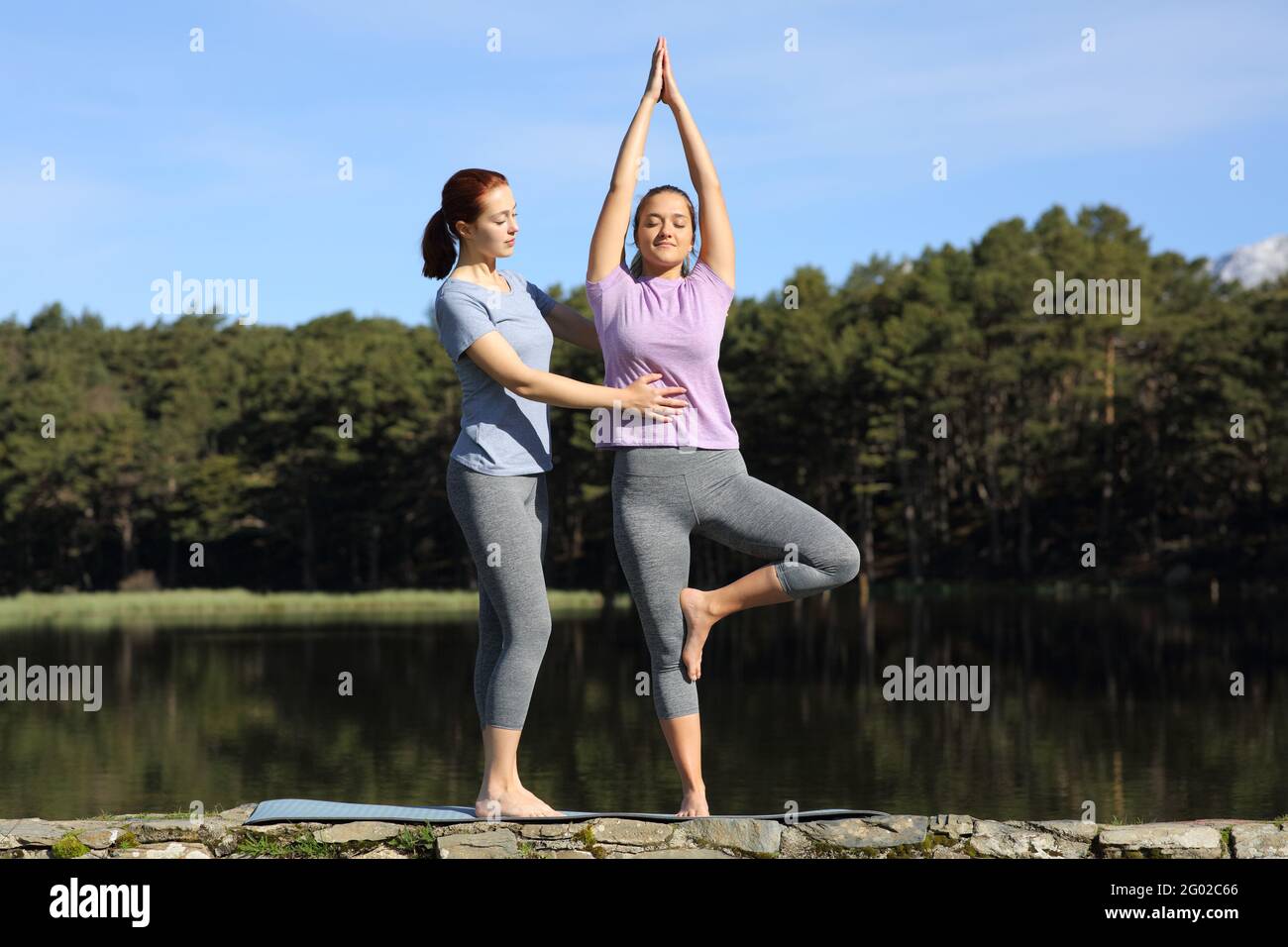 Front view portrait of a yogi teaching yoga to a woman in a lake Stock Photo
