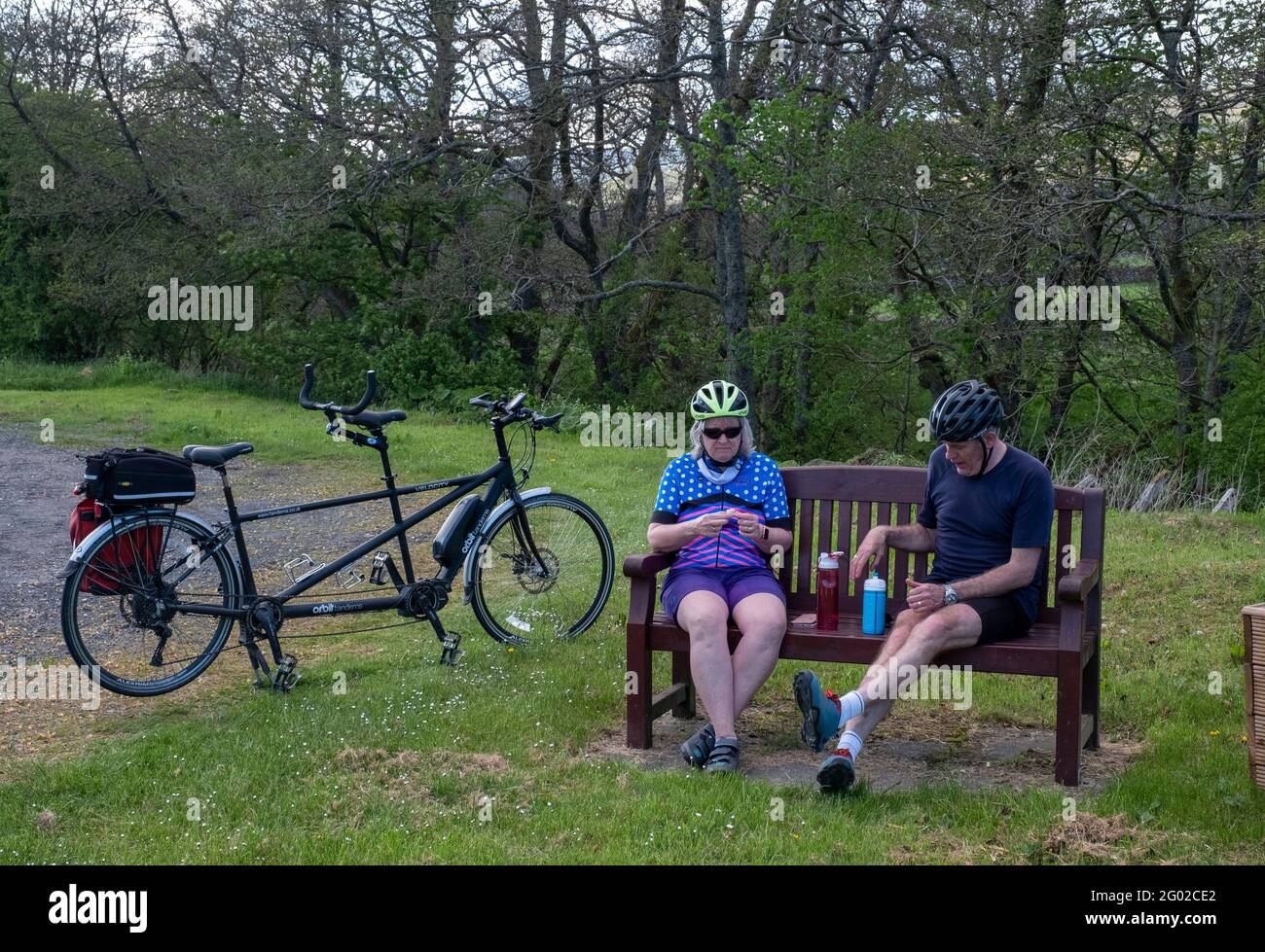 A couple on a tandem stop off for a drink near Hermitage Castle in the Liddesdale valley, Newcastleton, Scottish Borders. Stock Photo