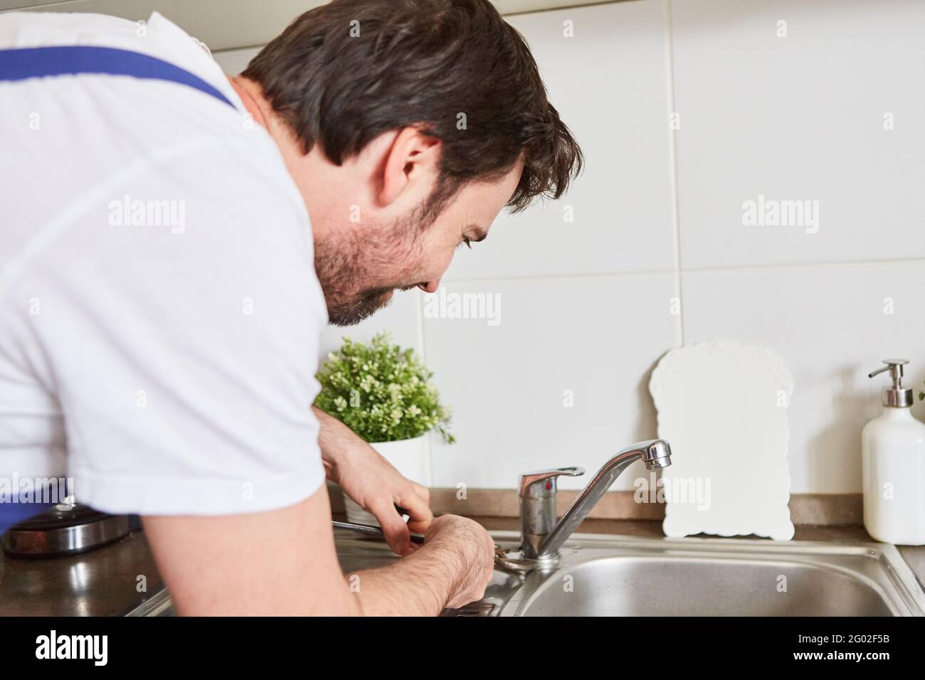 Professional plumber or do-it-yourselfer connecting the kitchen faucet to the sink Stock Photo