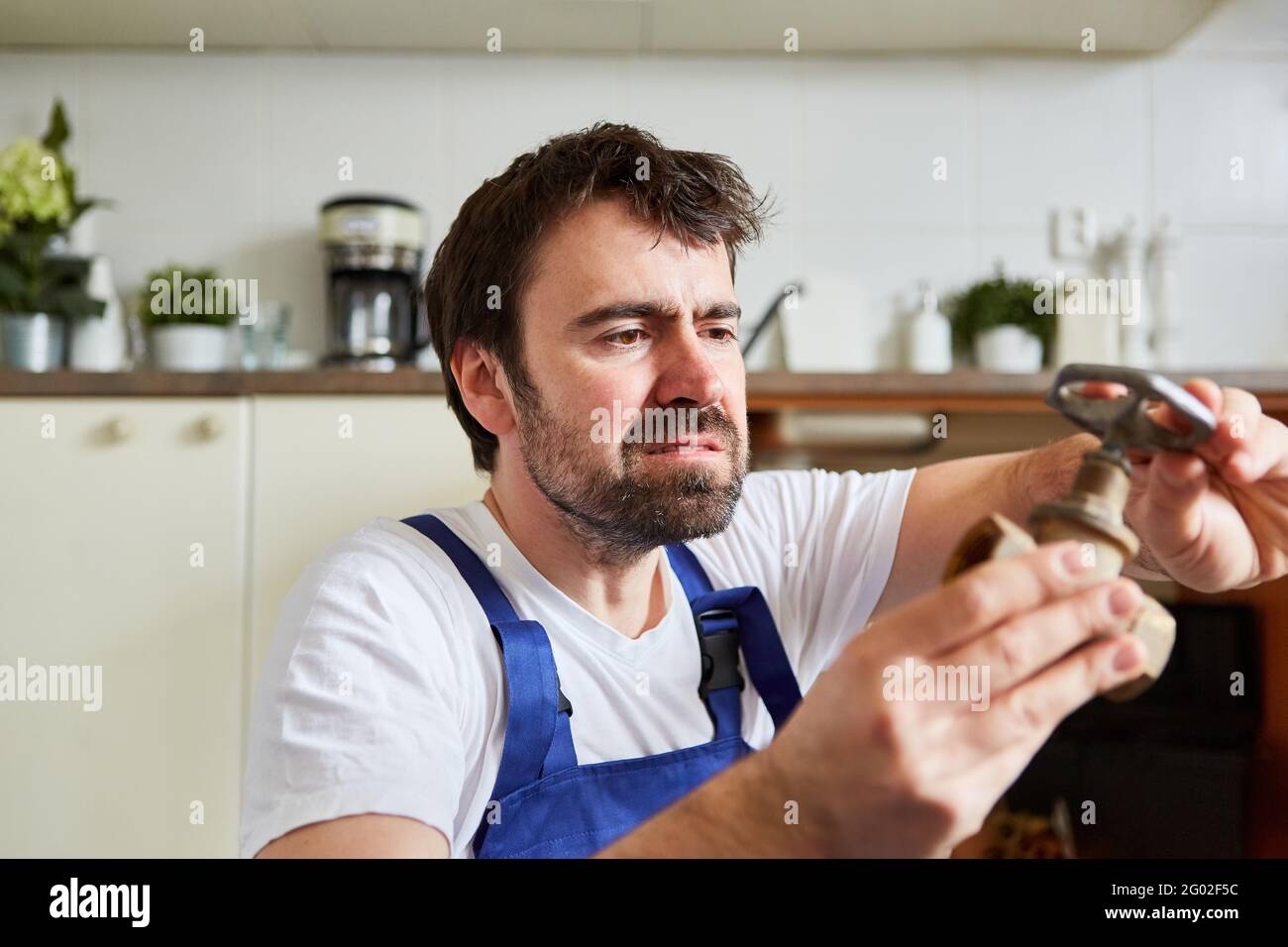 Do-it-yourselfer looks at defective shut-off valve when repairing a kitchen sink Stock Photo