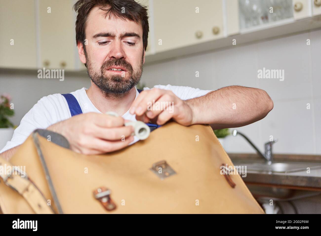 Do-it-yourselfer looks skeptical at a spare part for a kitchen sink repair Stock Photo