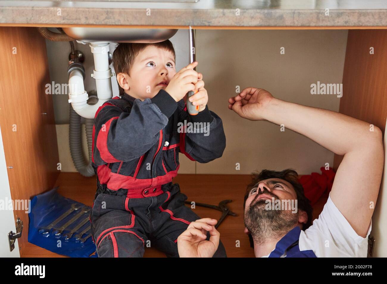 Handyman child helps his father install or repair a sink Stock Photo