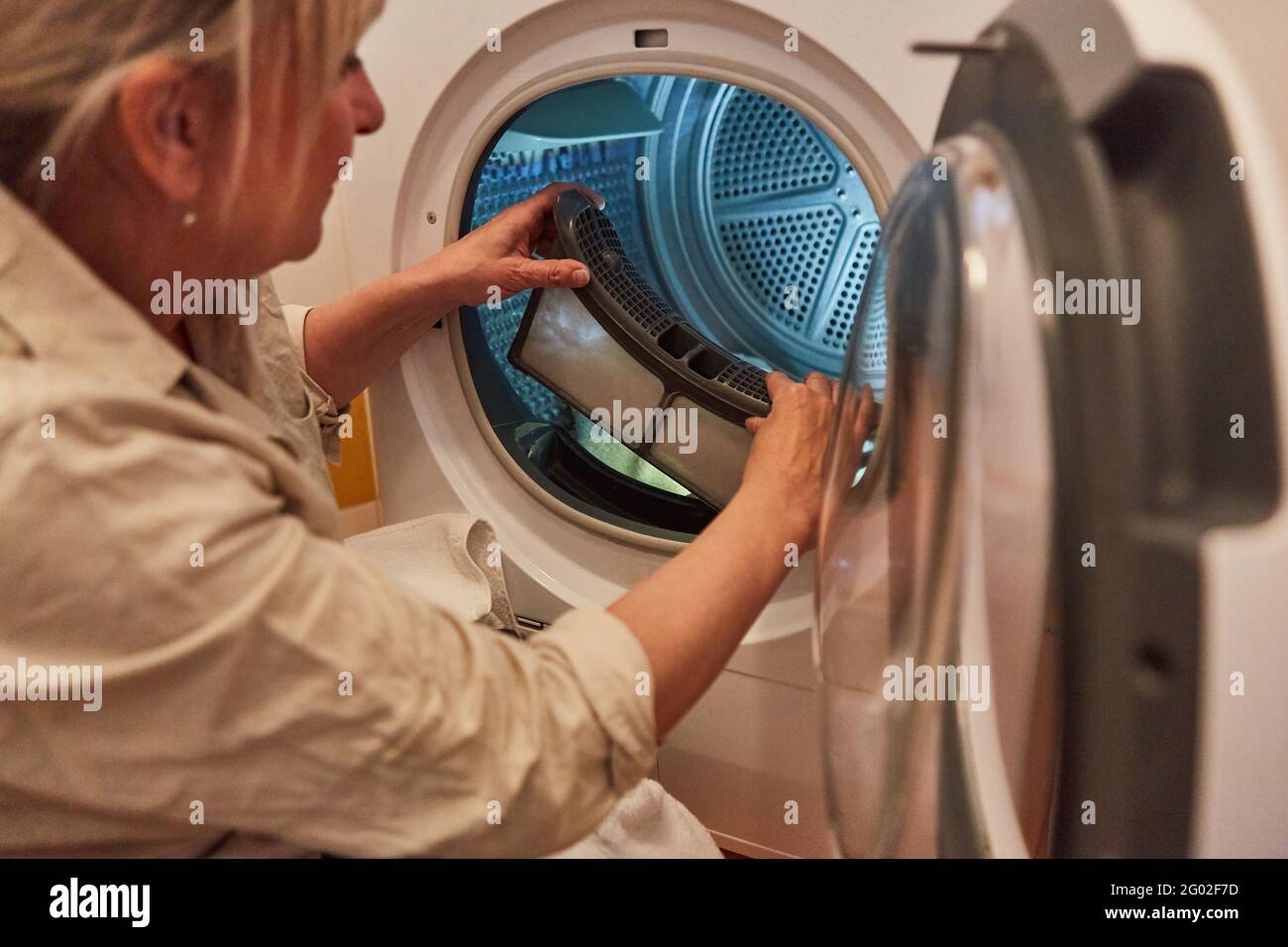 https://c8.alamy.com/comp/2G02F7D/a-housewife-woman-cleans-the-lint-filter-of-the-washing-machine-or-tumble-dryer-2G02F7D.jpg
