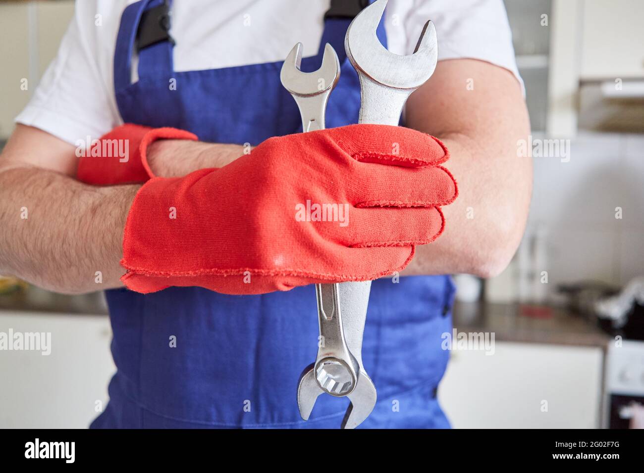 Craftsman with red gloves holds wrench as a symbol of craft Stock Photo