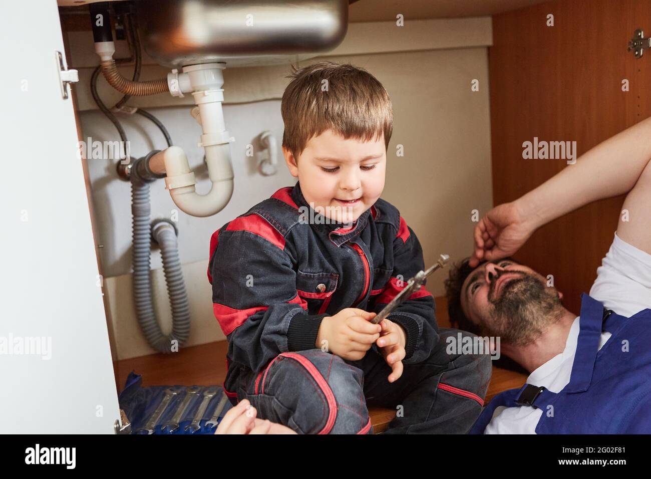 Boy helps father install or repair a sink in the kitchen Stock Photo