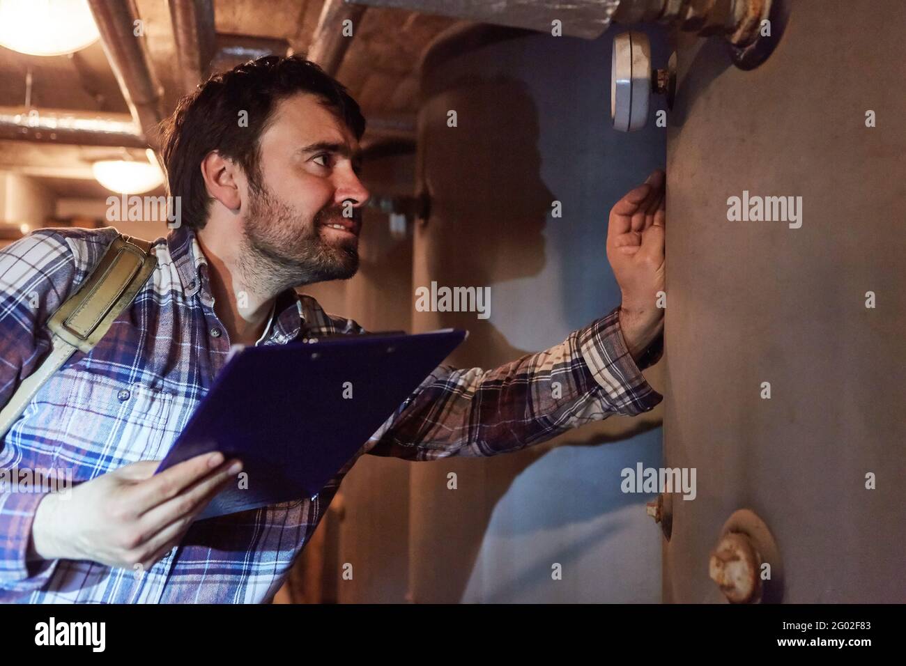 A heating fitter with a checklist checks the condensing boiler of a gas