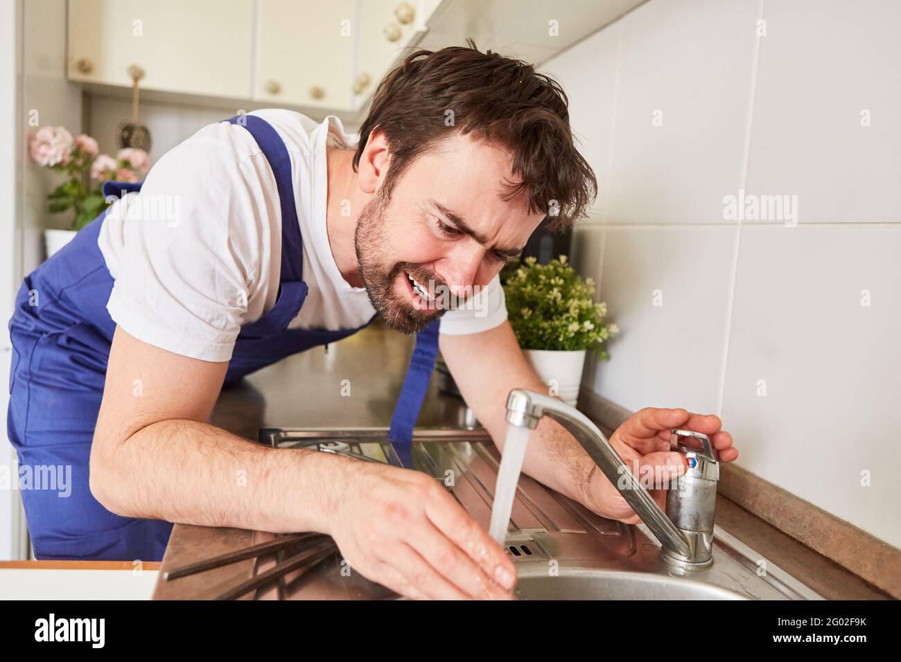 Plumber or do-it-yourselfer controls water flow at the kitchen sink tap Stock Photo