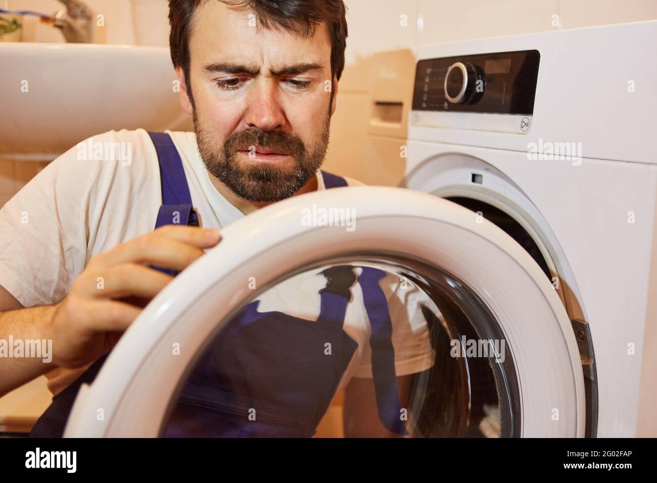 Do-it-yourselfer or plumber repairs defective clothes dryer in the laundry room Stock Photo