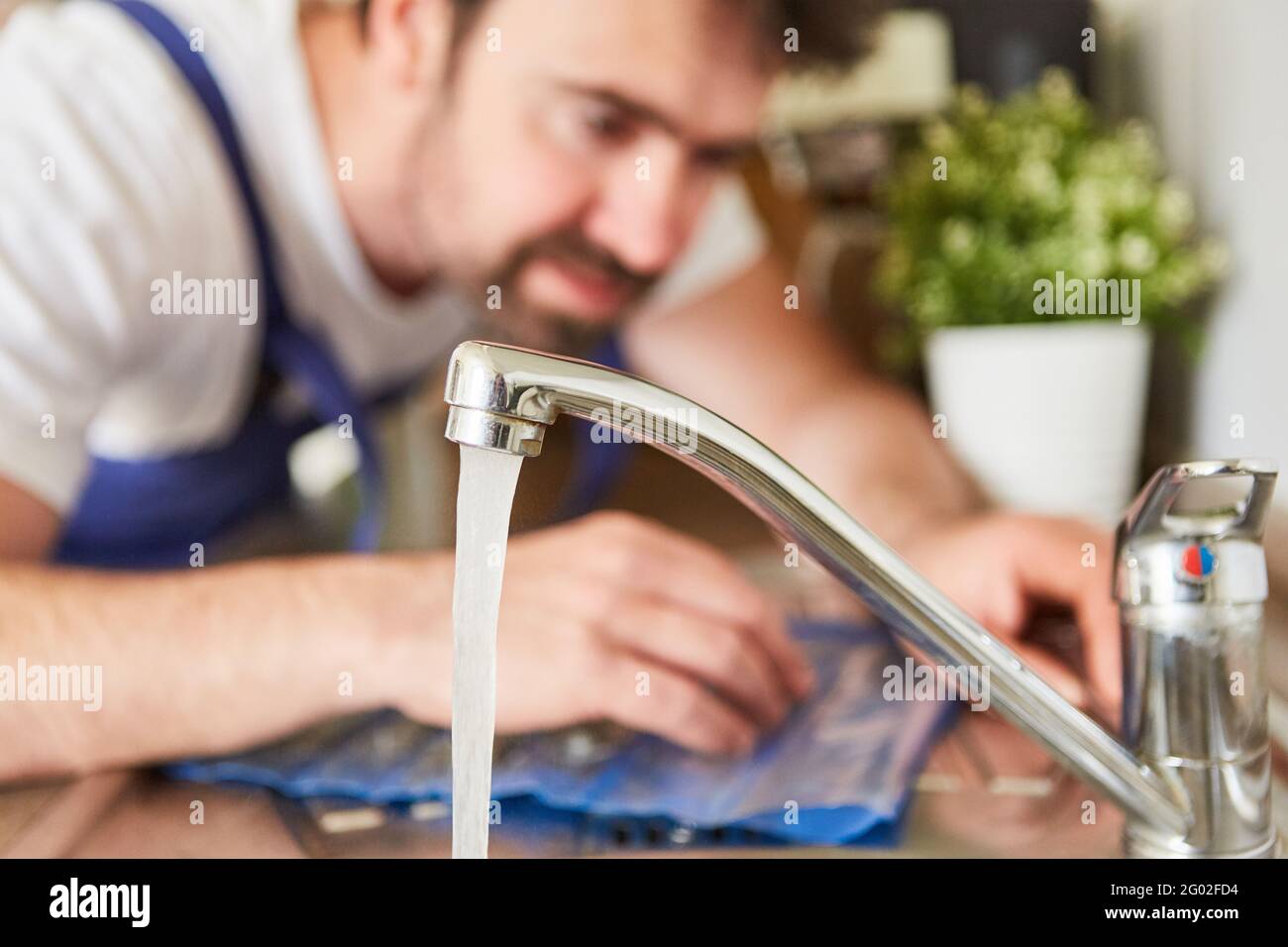 Craftsman or do-it-yourselfer checks mixer tap for hot water at the sink Stock Photo