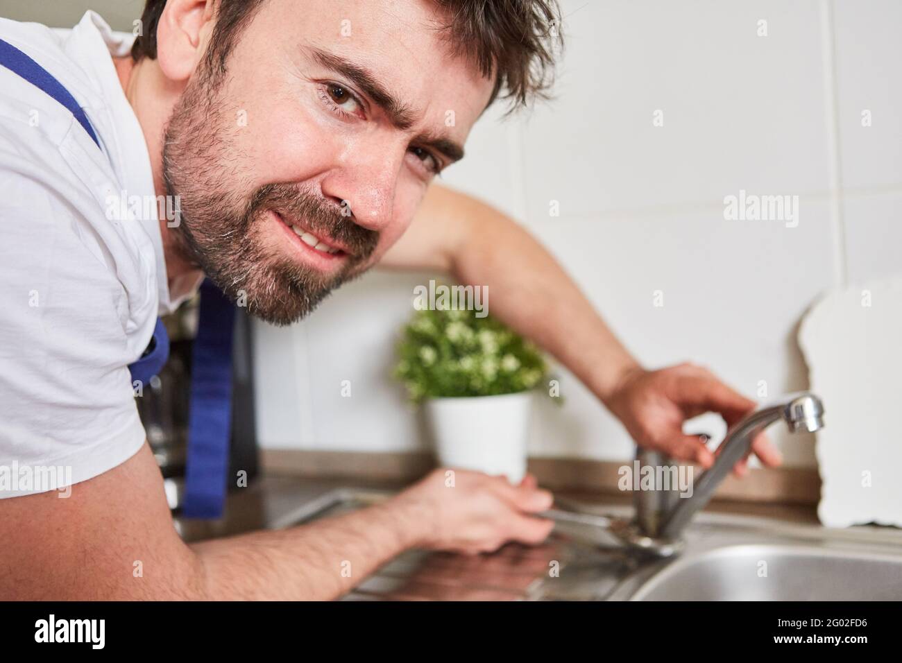 Plumber connecting kitchen faucets to the sink in a kitchen Stock Photo
