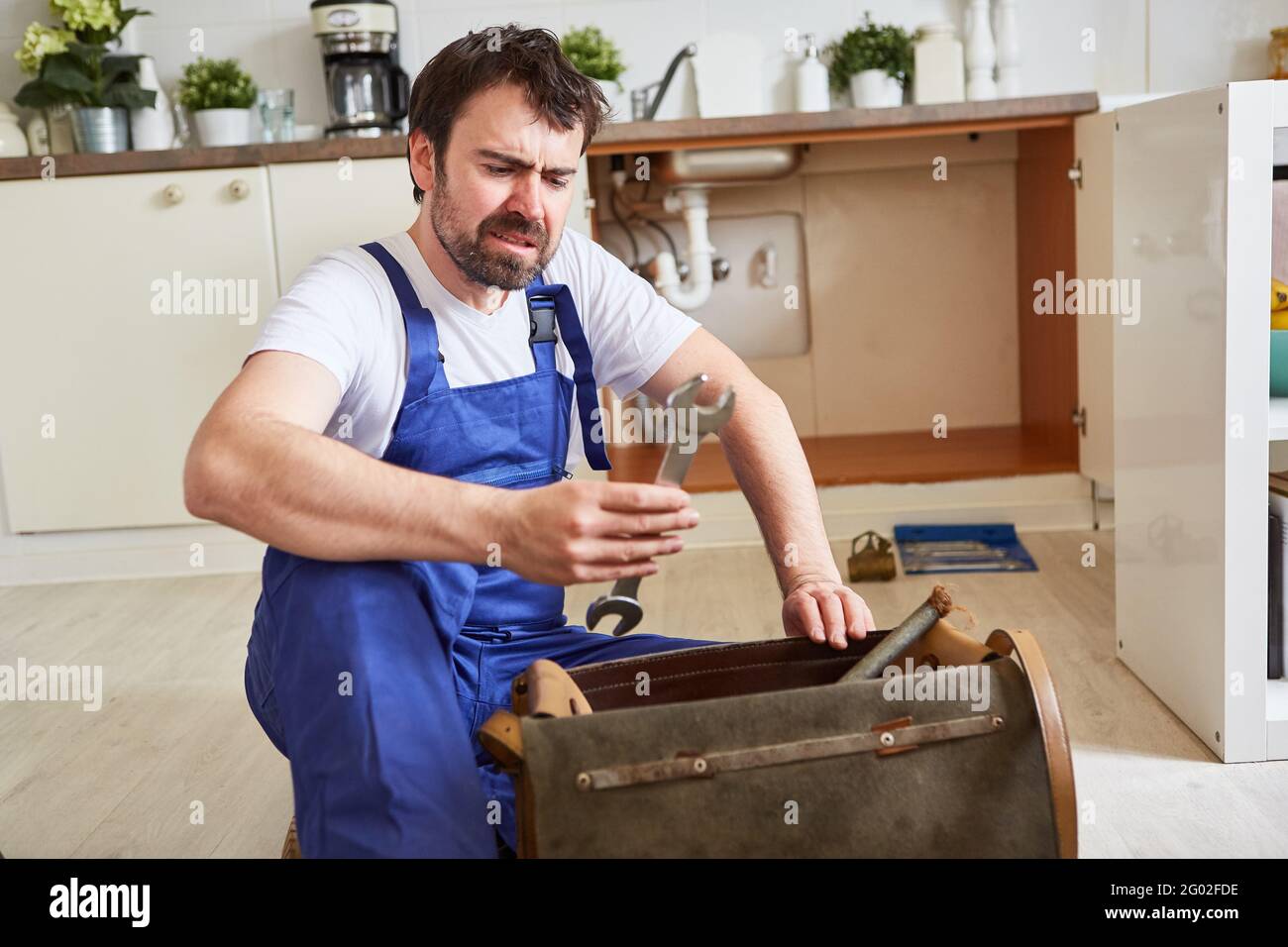 Do-it-yourselfer looks uncertainly at the wrench to repair the sink Stock Photo