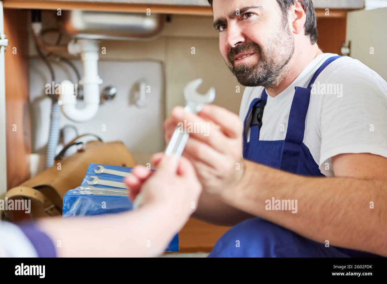 Do-it-yourselfer looks uncertain while repairing a sink in the kitchen Stock Photo