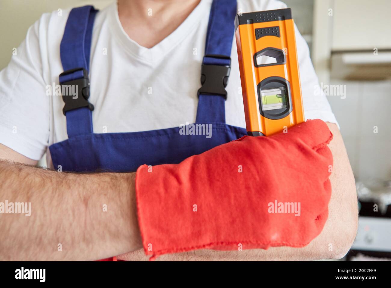Craftsman with spirit level and gloves as a symbol of craftsmanship and precision Stock Photo