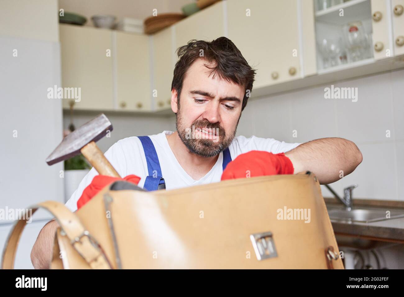 Do-it-yourselfer looks uncertainly for tools for repair in his tool bag Stock Photo