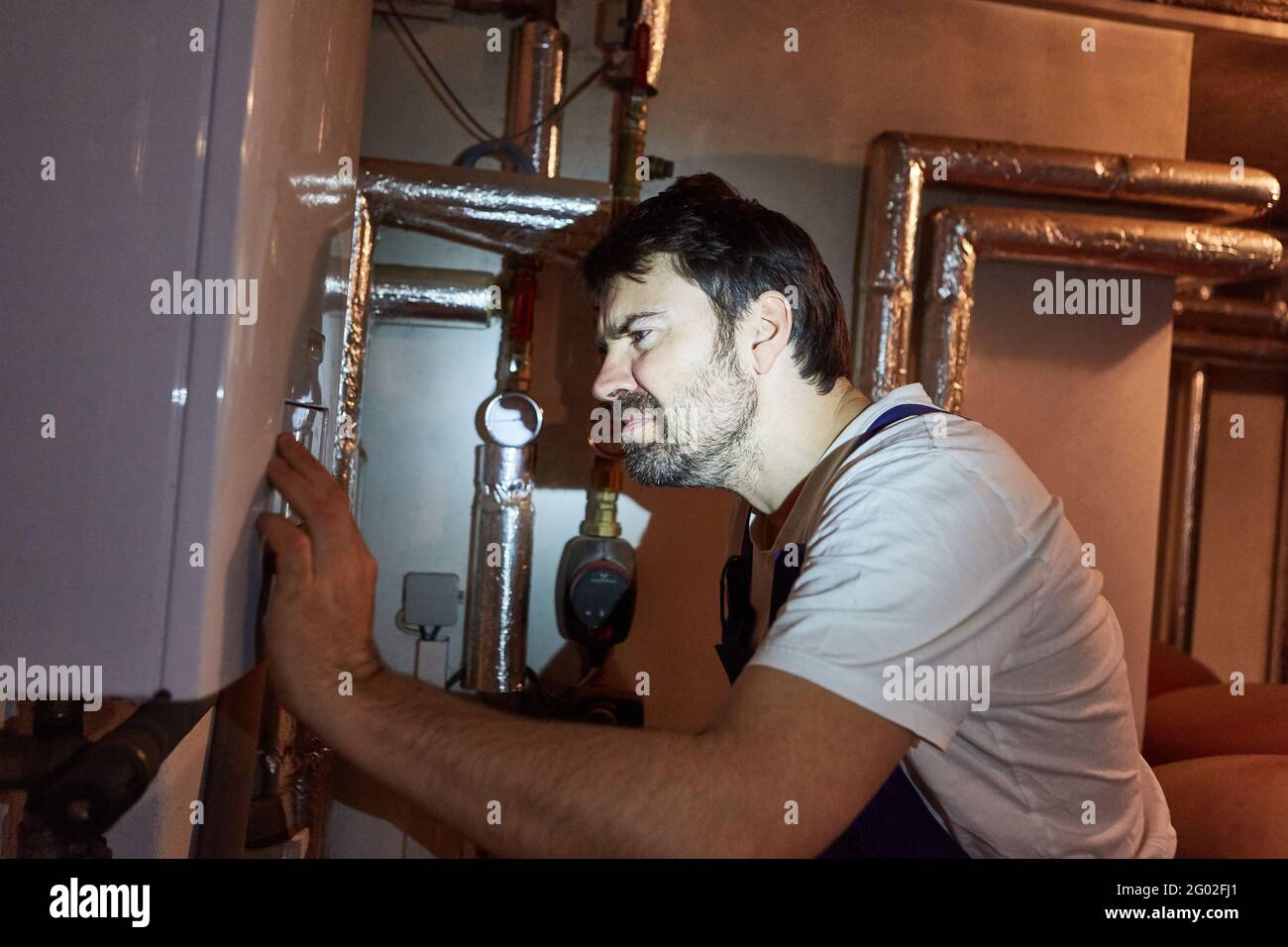 Installer checks the installation of the gas boiler in the basement during heating maintenance Stock Photo