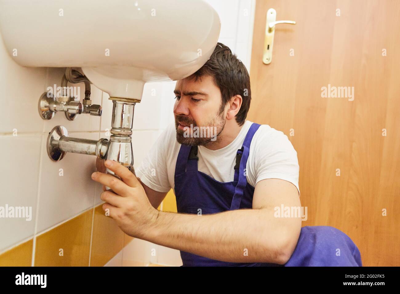 Do-it-yourselfer or plumber repairs broken drain on bathroom sink Stock Photo
