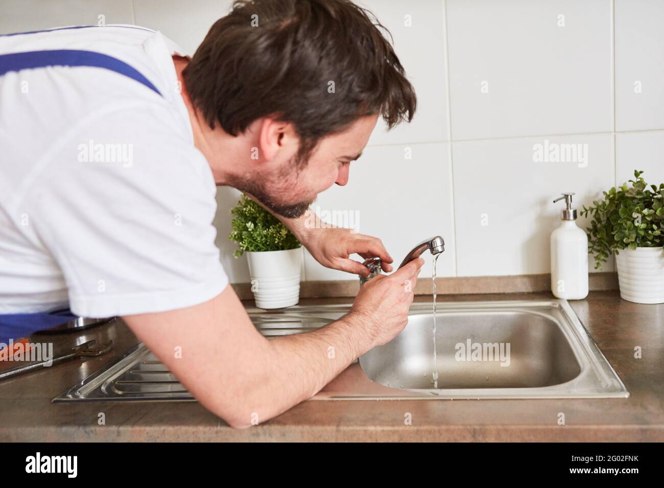 Craftsman repairing a leaky faucet on the kitchen sink Stock Photo Alamy