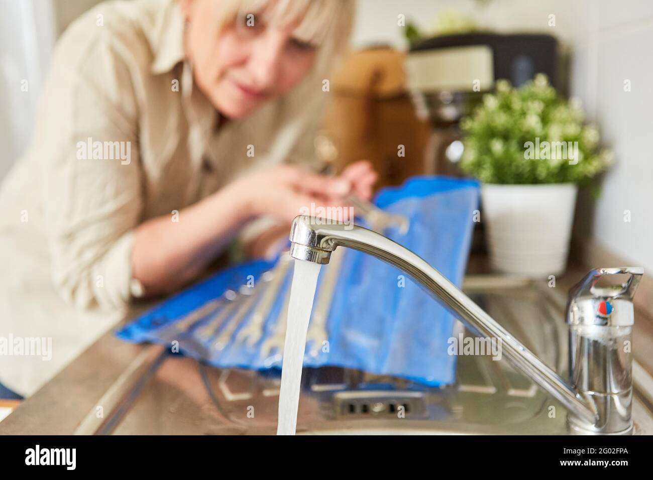 Do-it-yourself woman repairing the mixer tap on the faucet at the sink Stock Photo