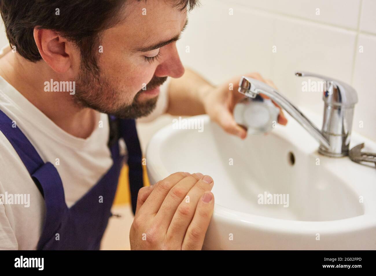Do-it-yourselfer or plumber repairs the tap and tap on the sink Stock Photo