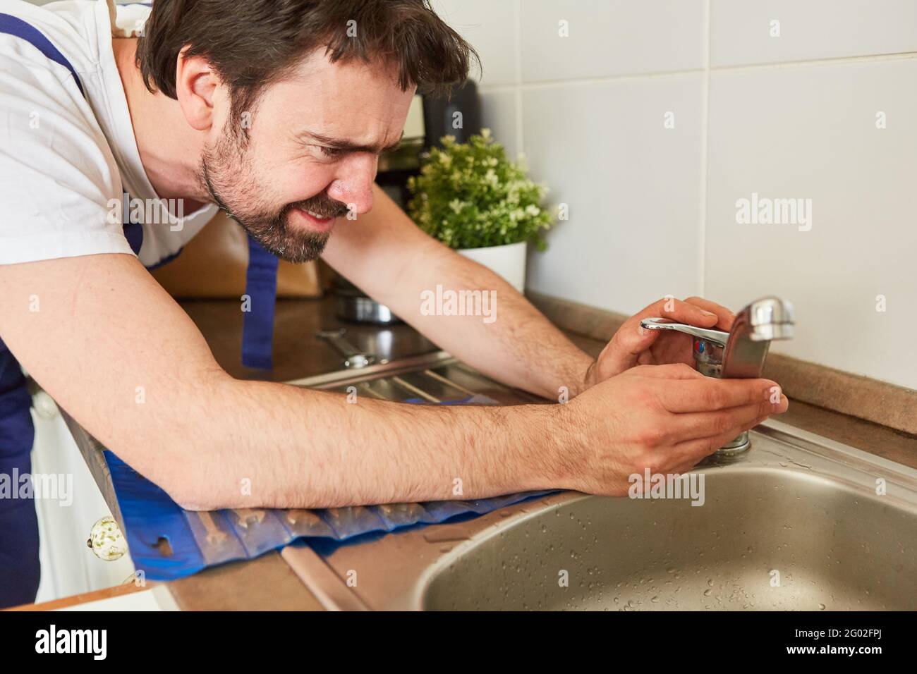 Do-it-yourselfer or plumber repairs the tap on the sink in the kitchen Stock Photo