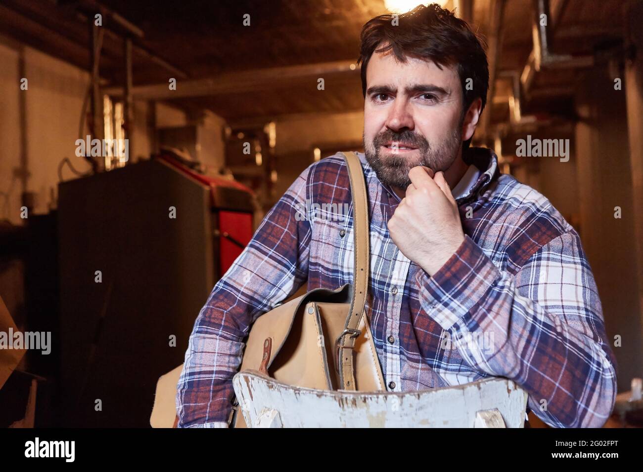 Man as a do-it-yourselfer in the boiler room in front of the gas heater has doubts Stock Photo