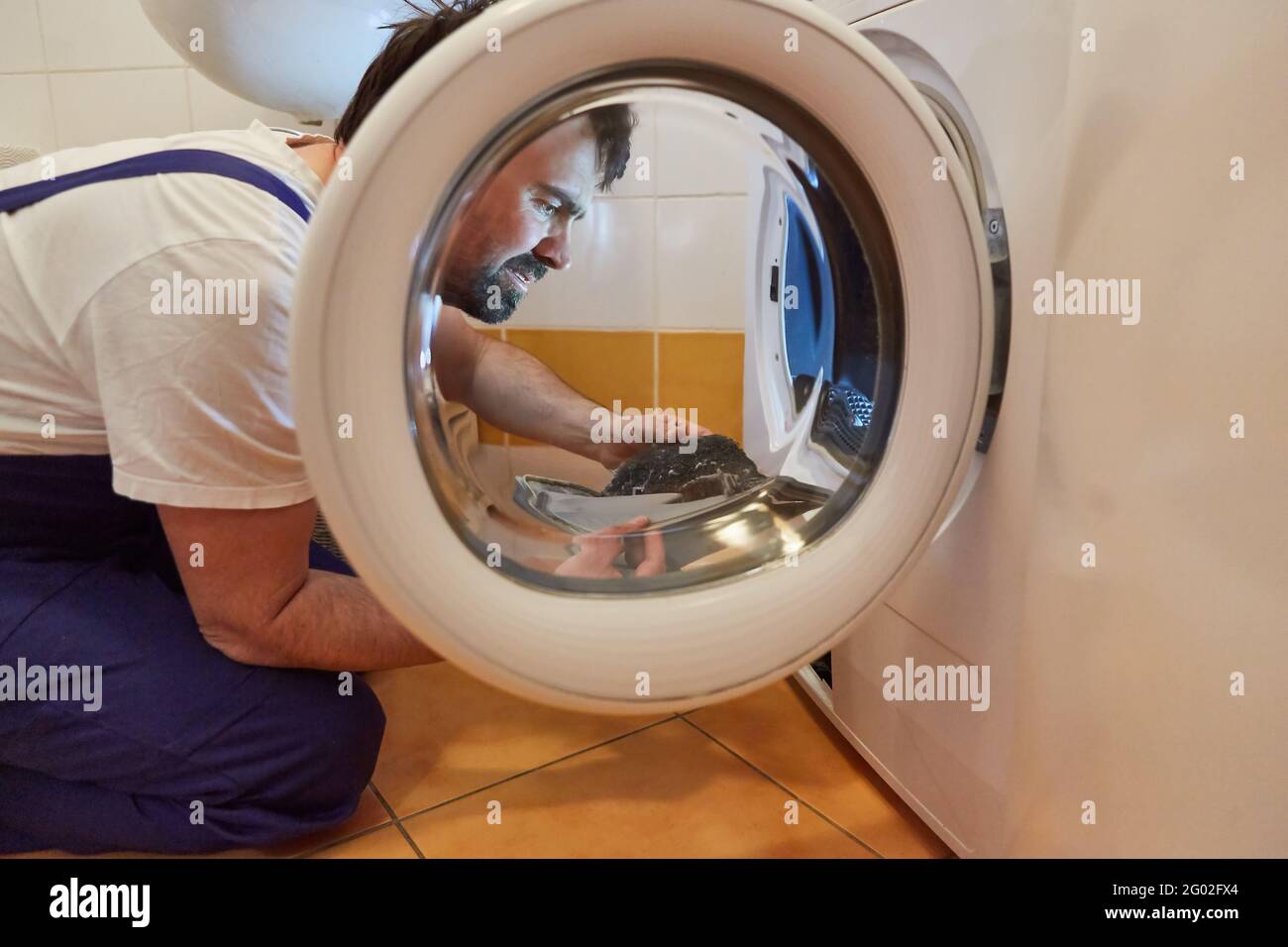 Craftsman cleaning lint filter from a tumble dryer in a laundry room