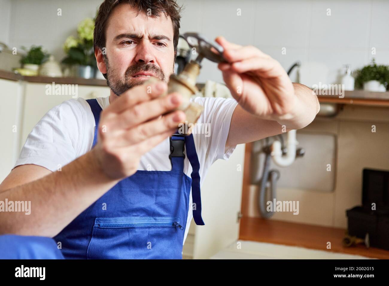 Handyman holds a broken shutoff valve while repairing the kitchen sink