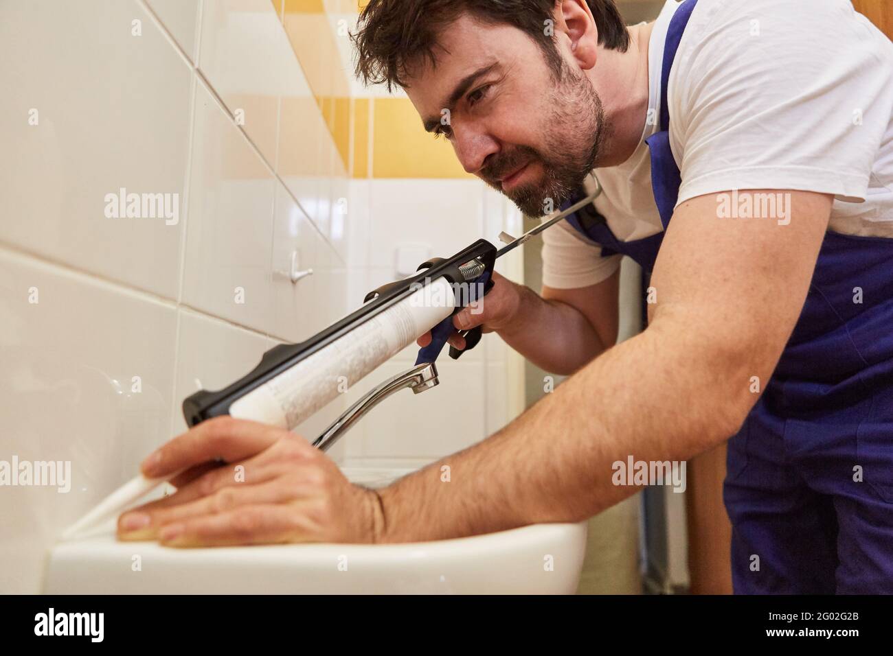 Do-it-yourselfer uses cartridge gun to seal joints with silicone on the sink Stock Photo
