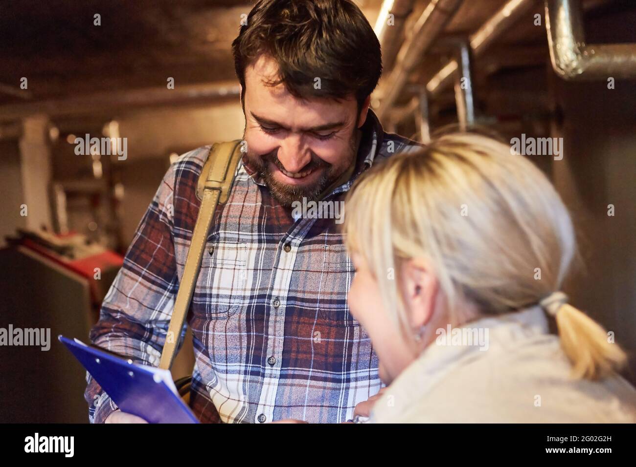Heating installer talking to a customer in the basement after heating maintenance Stock Photo