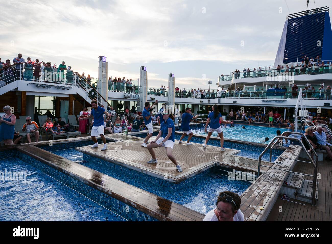Cruise ships Azura and Britannia dancing singing staff on ships  people sing dance wave sky weather water sea pool swim swimming sit sat watch funnel Stock Photo